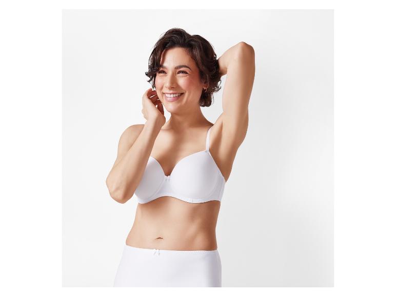 Eine Frau lächelt, während sie einen weißen BH und einen hoch taillierten Unterwäsche trägt.