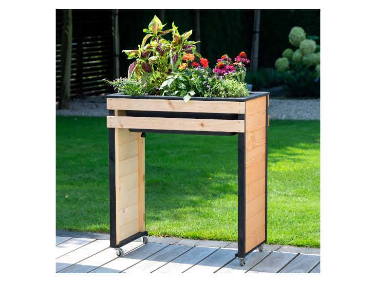 Hölzernes Hochbeet auf Rollen mit verschiedenen bunten Blumen und Pflanzen im Garten.