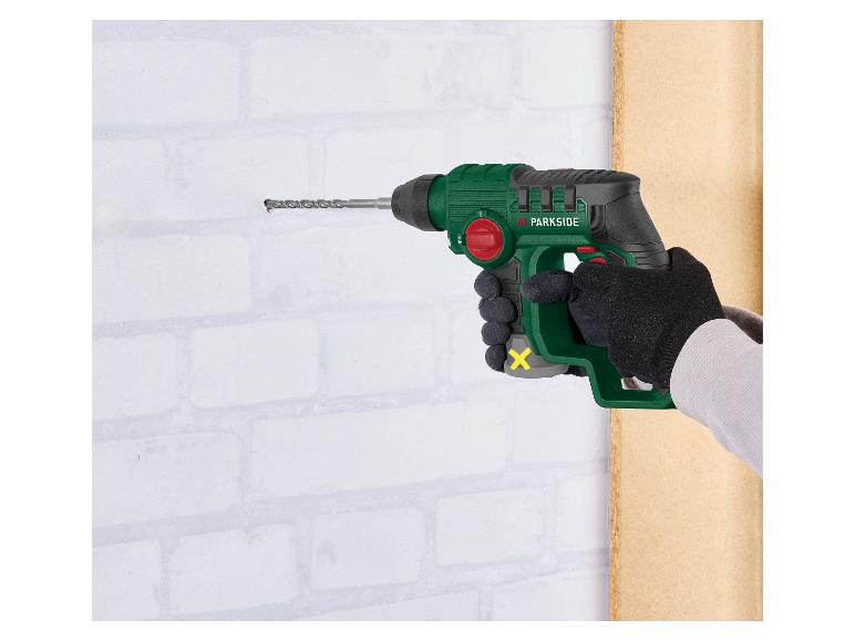 Handbohrmaschine bohrt ein Loch in eine weiße Ziegelwand.