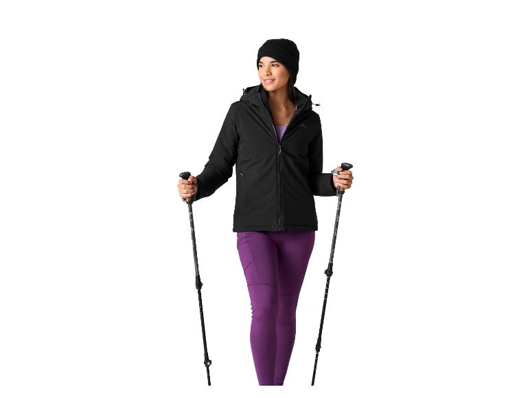 Frau in schwarzer Jacke und lila Leggings mit Wanderstöcken.