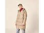 Frau in beiger Daunenjacke, rotem Rollkragenpullover und Mütze