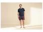 Mann in marineblauem T-Shirt und roten karierten Shorts.
