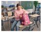 Ein Mädchen sitzt auf einem Schreibtisch und öffnet ihren rosa CRELANDO® Schulrucksack.