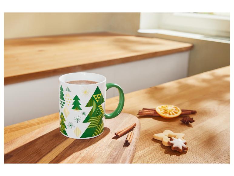 Heißer Kakao in einer Weihnachtstasse, mit Zimt und Keksen auf einem Holztisch.