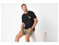 Mann sitzt in schwarzem 'ROAD TRIPPIN' T-Shirt und khakifarbenen Shorts.