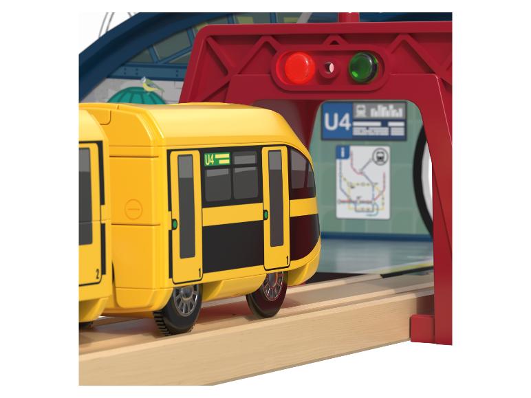 Ein gelber Holzzug fährt über eine Schiene.