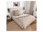 Modernes Schlafzimmer mit beigem Bett, passender Bettwäsche, Nachttisch und Kommode.