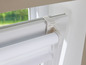 Ein weißer Rollladen mit Kettenzug, an einem Fenster befestigt.