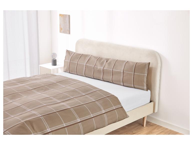 Bett mit beigem Kopfteil und kariertem Bettbezug und Kissenbezug.