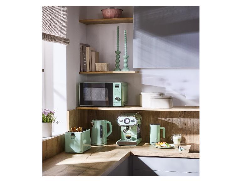 Mintgrüne Küchengeräte: Mikrowelle, Toaster, Wasserkocher und Espressomaschine auf einer Holztheke.