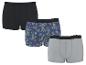 Drei Herren-Baumwollboxershorts: eine schwarze, eine mit Ananas- und Palmenmuster und eine graue.
