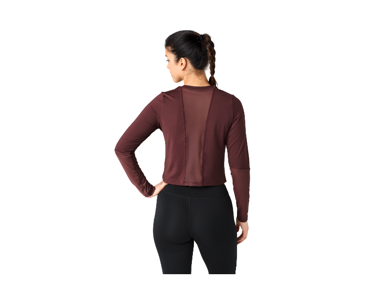 Frau in einem dunkelroten Langarm-Oberteil und schwarzen Leggings.