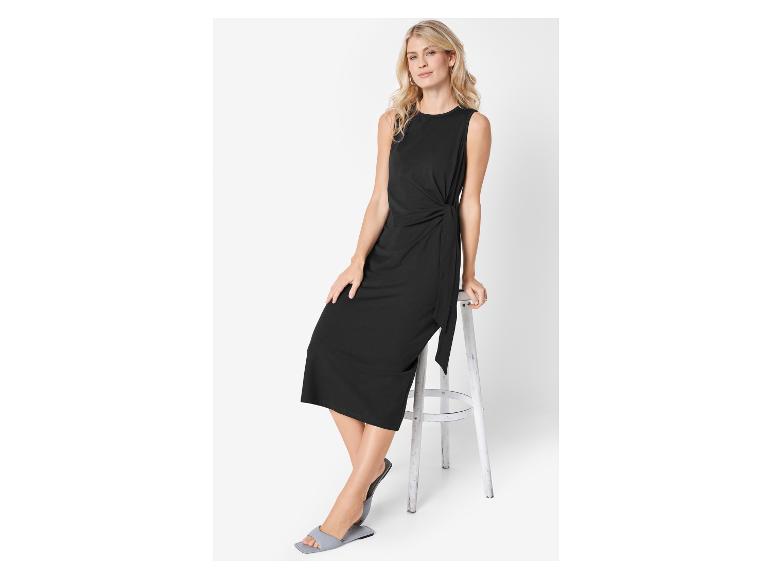 Elegantes Damenoutfit: schwarzes Wickelkleid und flache Sandalen.