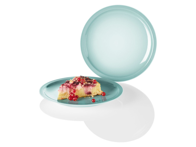 Ein Stück Kuchen mit roten Beeren auf einem hellblauen Teller.