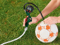 Person pumpt Fußball mit digitalem Manometer auf dem Rasen auf.