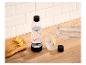 Sprudelwasserflasche und Glas mit Eis und Zitrone auf einer Holztheke.