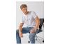 Mann in weißem T-Shirt und Jeans, sitzt auf einem Stuhl, blickt zur Seite.