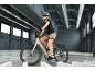 Frau auf einem E-Bike mit Helm und Sonnenbrille in einer Garage.