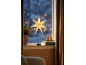 Leuchtender Weihnachtsstern auf einem Standfuß auf der Fensterbank.