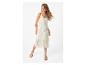 Frau in einem cremefarbenen Strickkleid und flachen Sandalen.