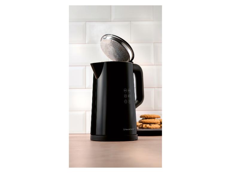 Schwarzer Wasserkocher mit offenem Deckel und Keksen auf einem Holztisch.