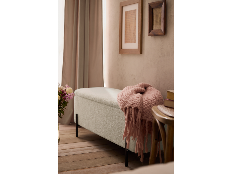 Gepolsterte Bank mit rosa Decke, gerahmte Kunst an der Wand und Vorhänge in einem Raum.