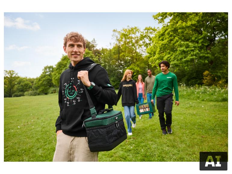Mann in schwarzem Hoodie mit grüner Kühltasche, spaziert mit Freunden im Park.