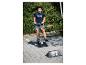 Junge auf einem Roller, der über eine kleine Rampe fahren will, trägt ein dunkelblaues T-Shirt und gemusterte Shorts.