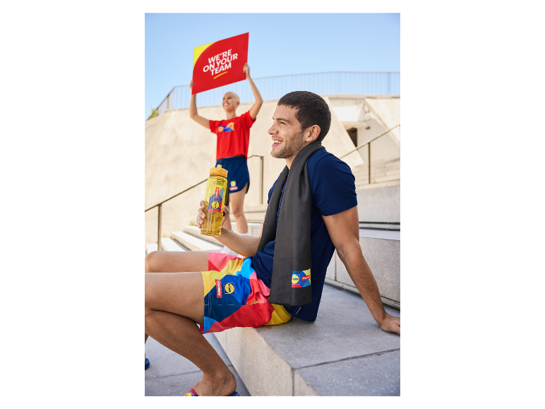 Mann mit Trek Lidl Shorts und Handtuch, hält Lidl Trinkflasche.