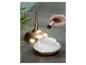 Hand fügt ätherisches Öl in einen goldfarbenen Aromadiffusor auf grauem Untergrund.