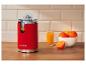 Rote Zitruspresse mit Orangensaft und Orangen auf einer Holztheke.