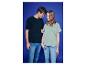 Lächelnder Mann und Frau in T-Shirts und Jeans, vor blauem Hintergrund.