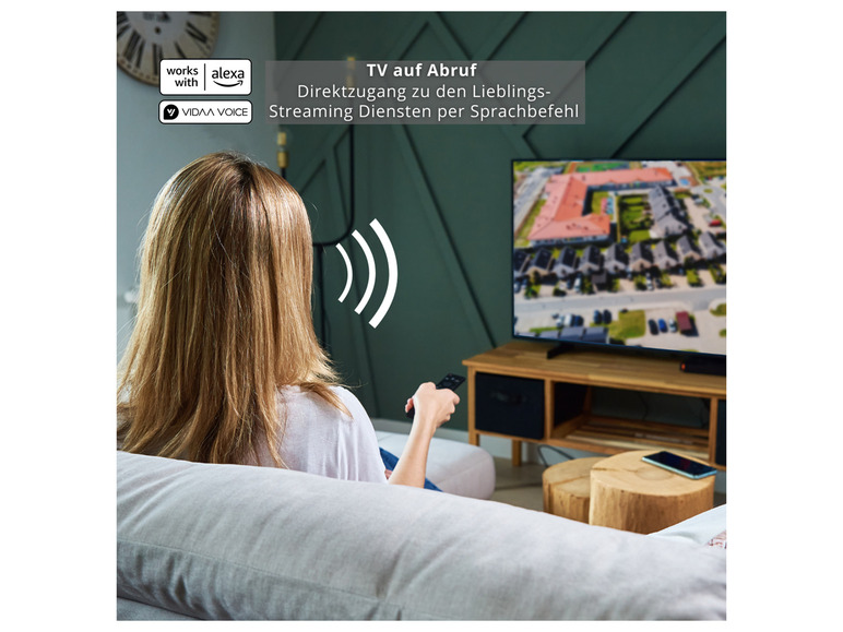 Frau auf der Couch mit einem Fernseher und einer Fernbedienung, funktioniert mit Alexa.