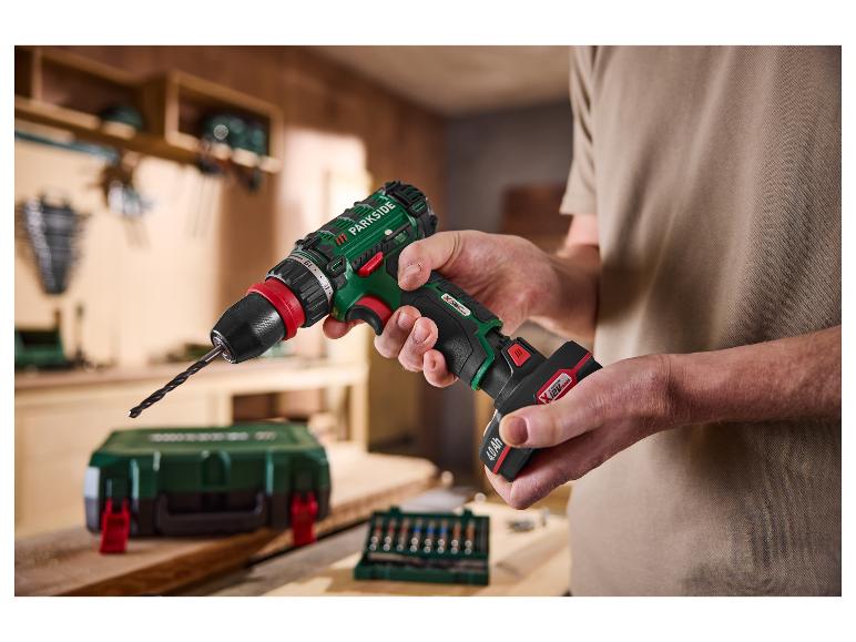 Mann hält einen PARKSIDE® 12 V Akku-Bohrschrauber mit 4 Ah Akku in einer Werkstatt.
