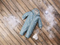 Ein blauer Baby-Overall mit Muster, Handschuhe und ein Schneeball.