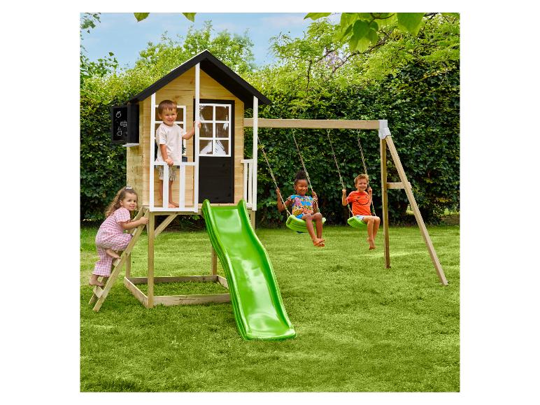 Kinder spielen auf einem Holzspielhaus mit Rutsche und Schaukeln im Garten.