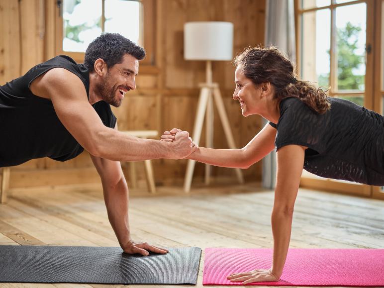 Ein Mann und eine Frau trainieren zusammen auf Yogamatten.