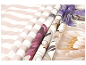 Gerollte Stoffe mit gestreiften, floralen und abstrakten Mustern in verschiedenen Farben.