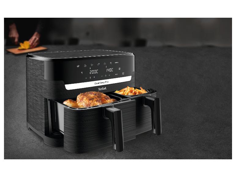 Tefal Dual Easy Fry Heißluftfritteuse mit Hähnchen und Pommes, mit einer Person, die im Hintergrund Obst schneidet.