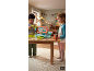 Kinder spielen mit einer Spielzeugkasse an einem Holztisch.