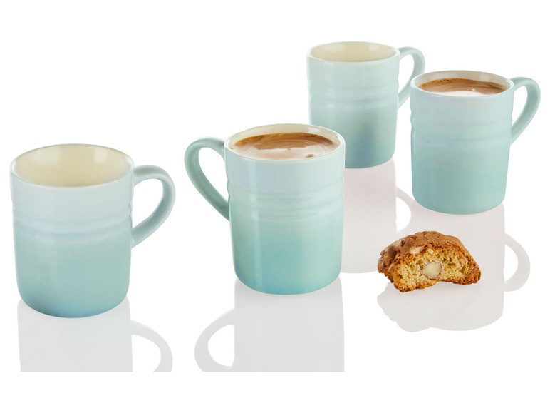 Vier blaue Le Creuset Tassen mit Kaffee und Biscotti.