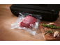 Vakuumverpacktes Fleisch mit Vakuumiergerät und Gewürzen auf Holzbrett.