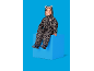 Lächelndes Kind in Leoparden-Schneeanzug, sitzt auf einem blauen Würfel.