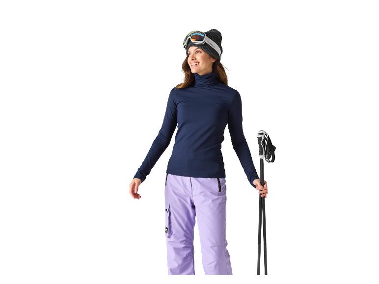 Skifahrerin mit Mütze, Skibrille, Rollkragenpullover und Skihose.