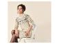 Frau in beigem Strickkleid mit Fair-Isle-Muster, auf einem Stuhl sitzend.
