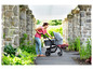 Eine Frau schiebt einen Graco-Kinderwagen durch einen Steinweg.
