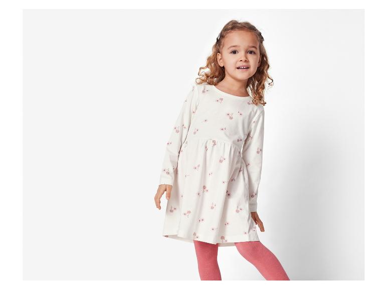 Mädchen in einem weißen Blumenkleid und rosa Strümpfen.