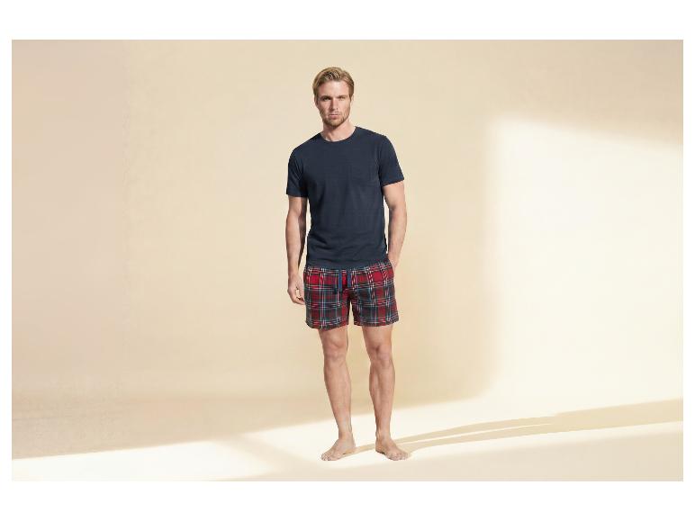 Mann in marineblauem T-Shirt und roten karierten Shorts.
