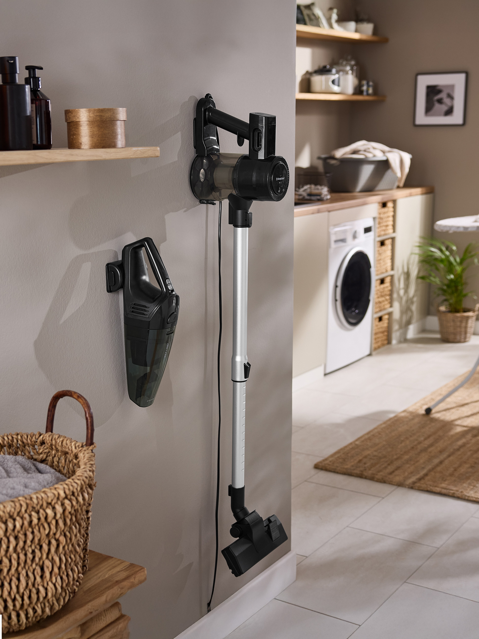 Zwei SilverCrest Staubsauger, ein Handstaubsauger und ein Stielstaubsauger, hängen an einer Wand im Hauswirtschaftsraum.