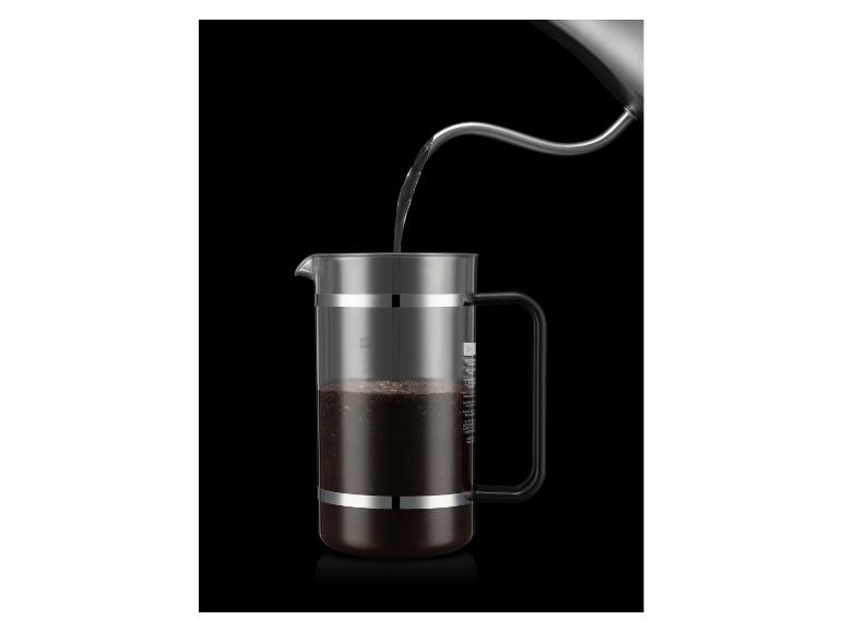 Wasser wird aus einem Wasserkocher in eine French Press Kaffeemaschine mit gemahlenem Kaffee gegossen.